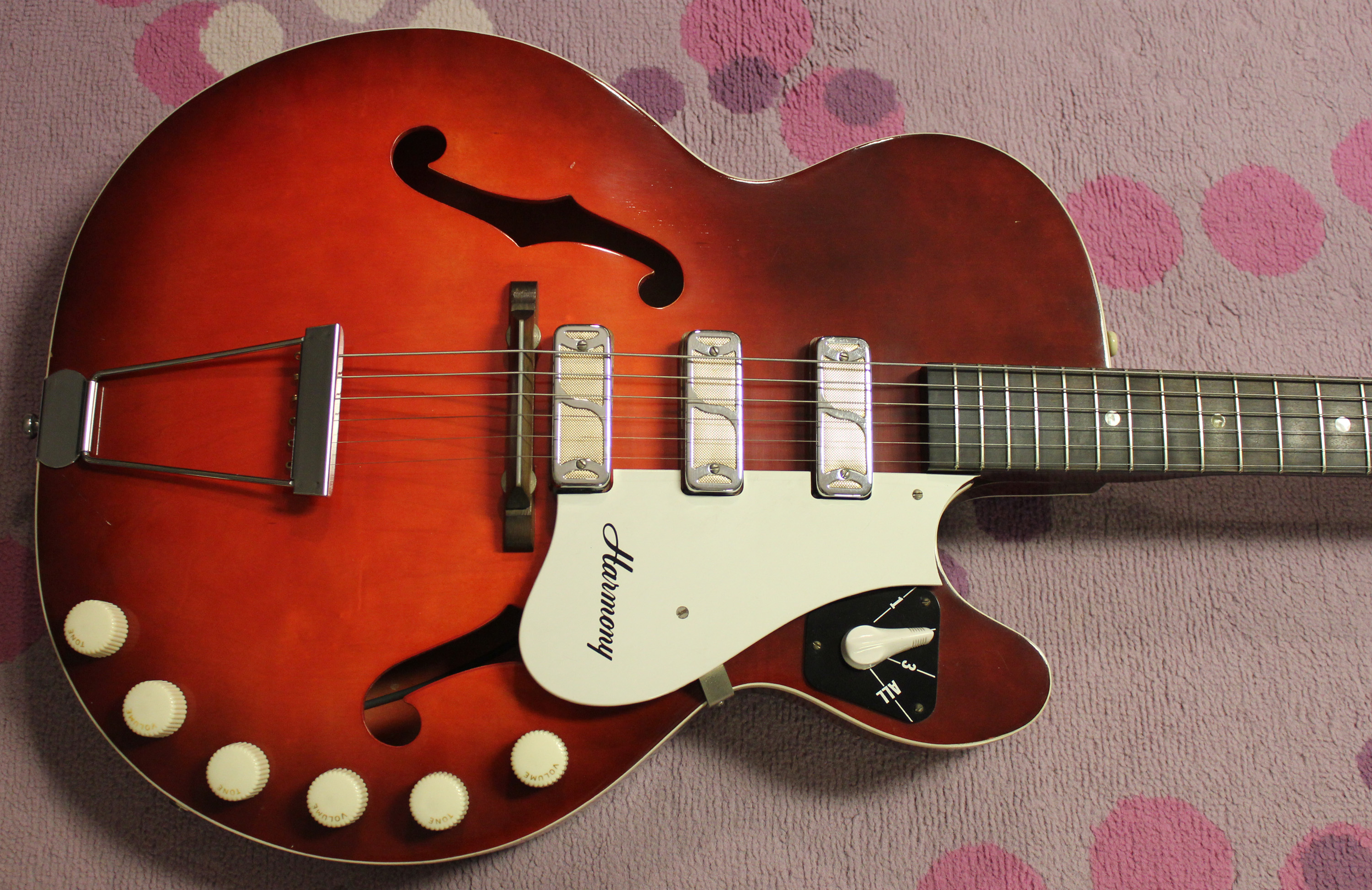 A vintage sunburst electric guitar on a stage riser under moody purple stage lights.